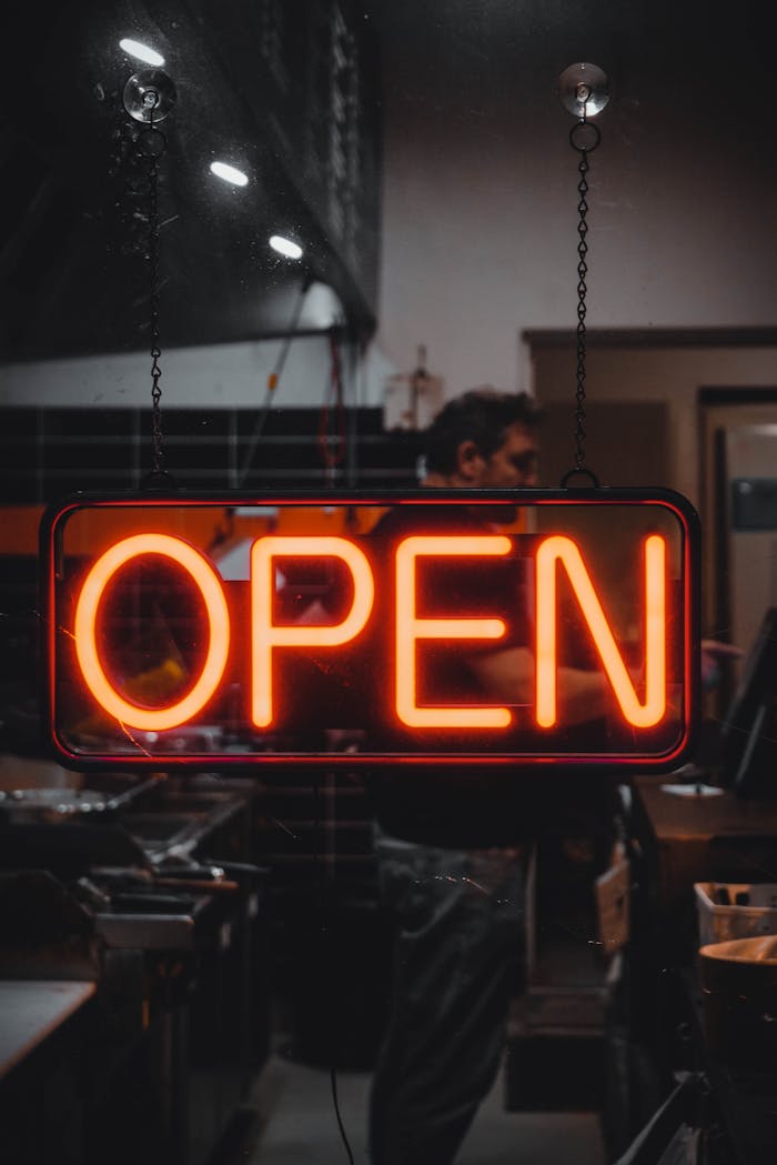 brand-01 A vibrant neon 'OPEN' sign glowing in a dimly lit store window, capturing a sense of nightlife and commerce.