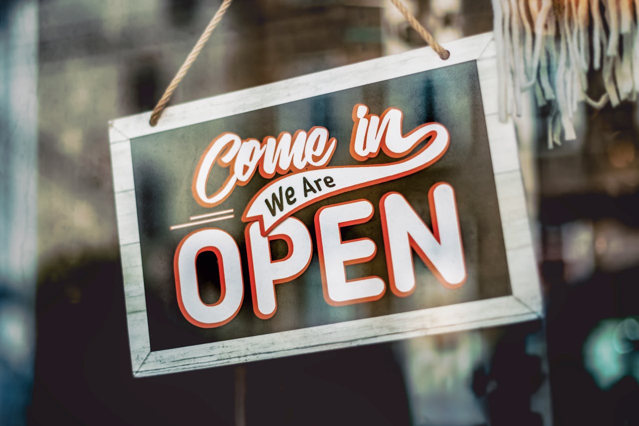 digital-01 A welcoming 'Come in, We Are Open' sign hanging on a glass window of an urban shop.