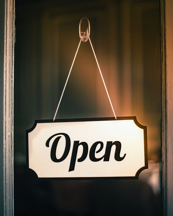 Vintage 'Open' sign hanging on a shop door signifying readiness for business.