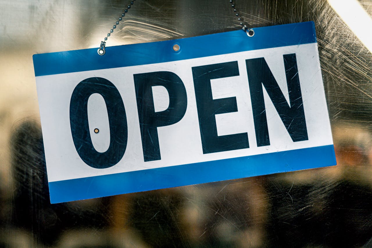 creative-03 A blue and white open sign hanging on a retail shop's glass door.
