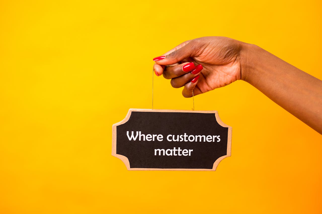 mobile-01 A close-up of a hand holding a sign stating Where customers matter against a bright yellow background.