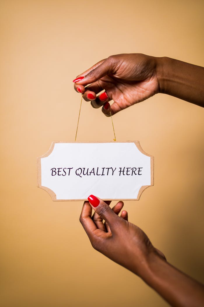 Crafting Captivating Headlines: Your awesome post title goes here Stylish female hands with red nails holding a sign that says 'Best Quality Here' against a soft background.