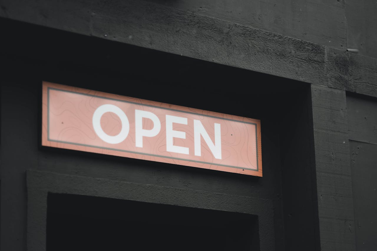 A striking image of an illuminated 'Open' sign on a dark building exterior, perfect for business themes.