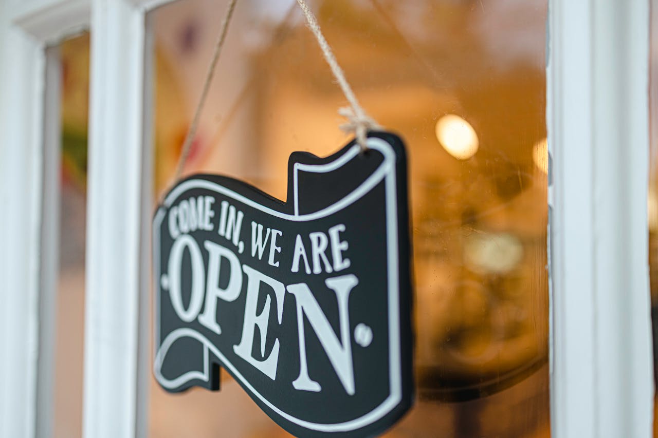 A welcoming open sign hanging on a glass door, inviting customers to enter.